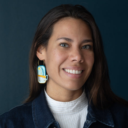 Smiling woman wearing hand-painted sardine can hoop earrings