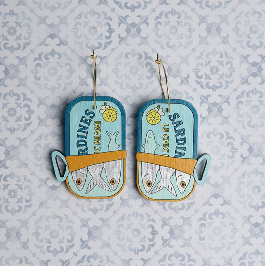 Hand-painted wooden sardine can hoop earrings by Le Chic Miami on patterned background
