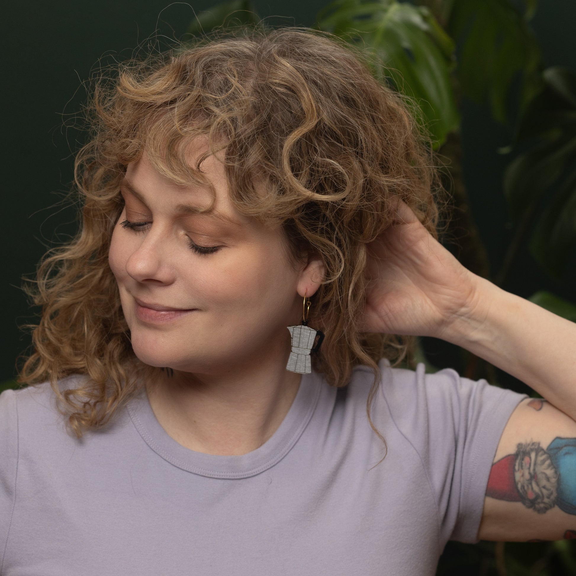 Woman wearing lilac shirt and hand-painted Moka Pot Hoop earring inspired by Cuban coffee, made by Le Chic Miami.